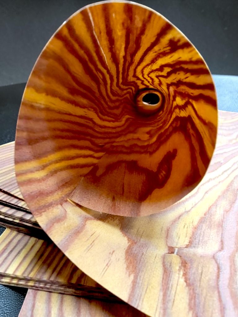 Easter red cedar thin wood sheet 1 - real wood paper Close-up of a polished wooden disc with orange-brown tiger-striped grain pattern.